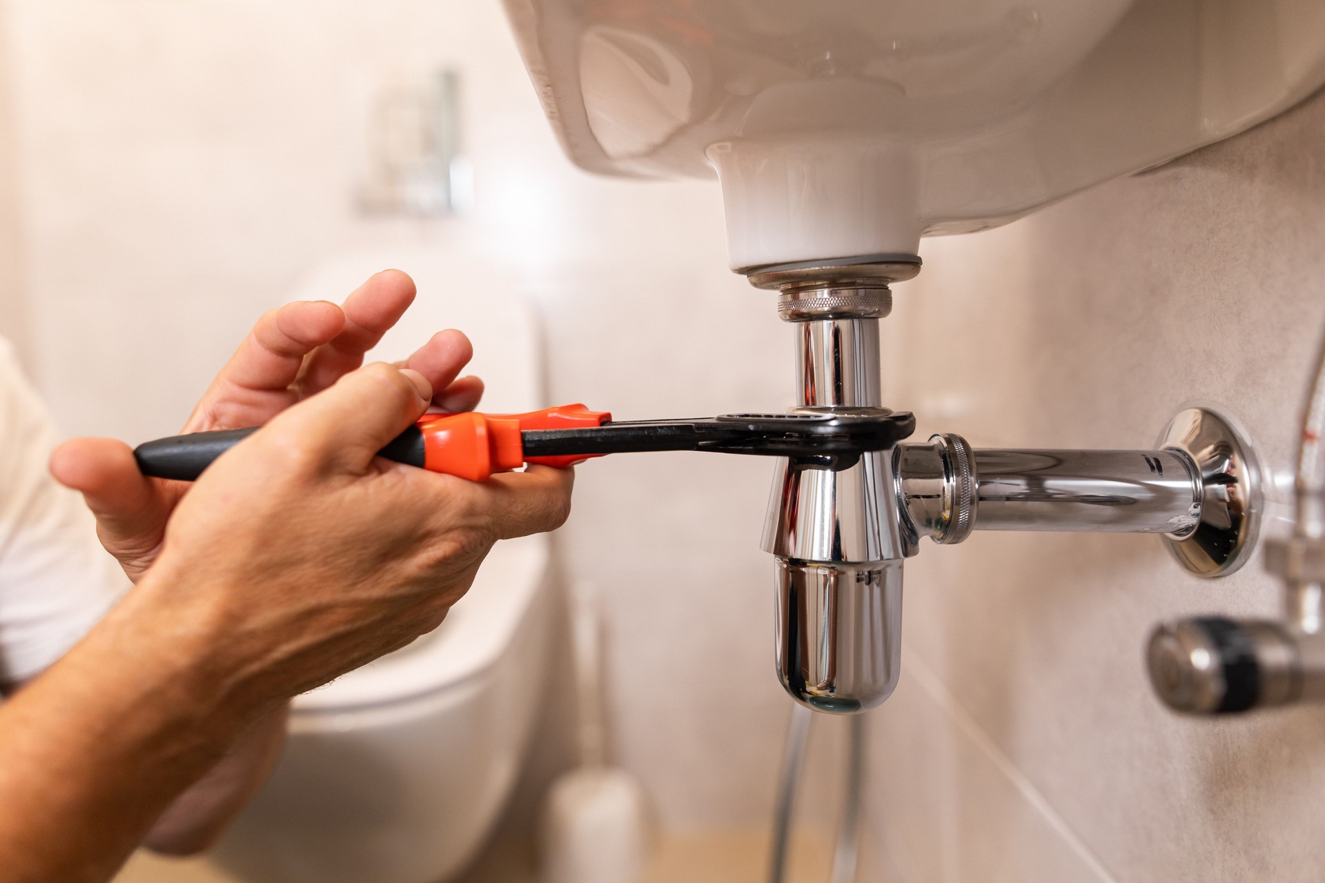 The plumber's hands using the wrench to fix the sink